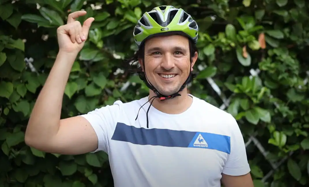 Ein American Express Mitarbeiter mit grünem Fahrradhelm vor einer grünen Hecke Ein American Express Mitarbeiter mit grünem Fahrradhelm vor einer grünen Hecke