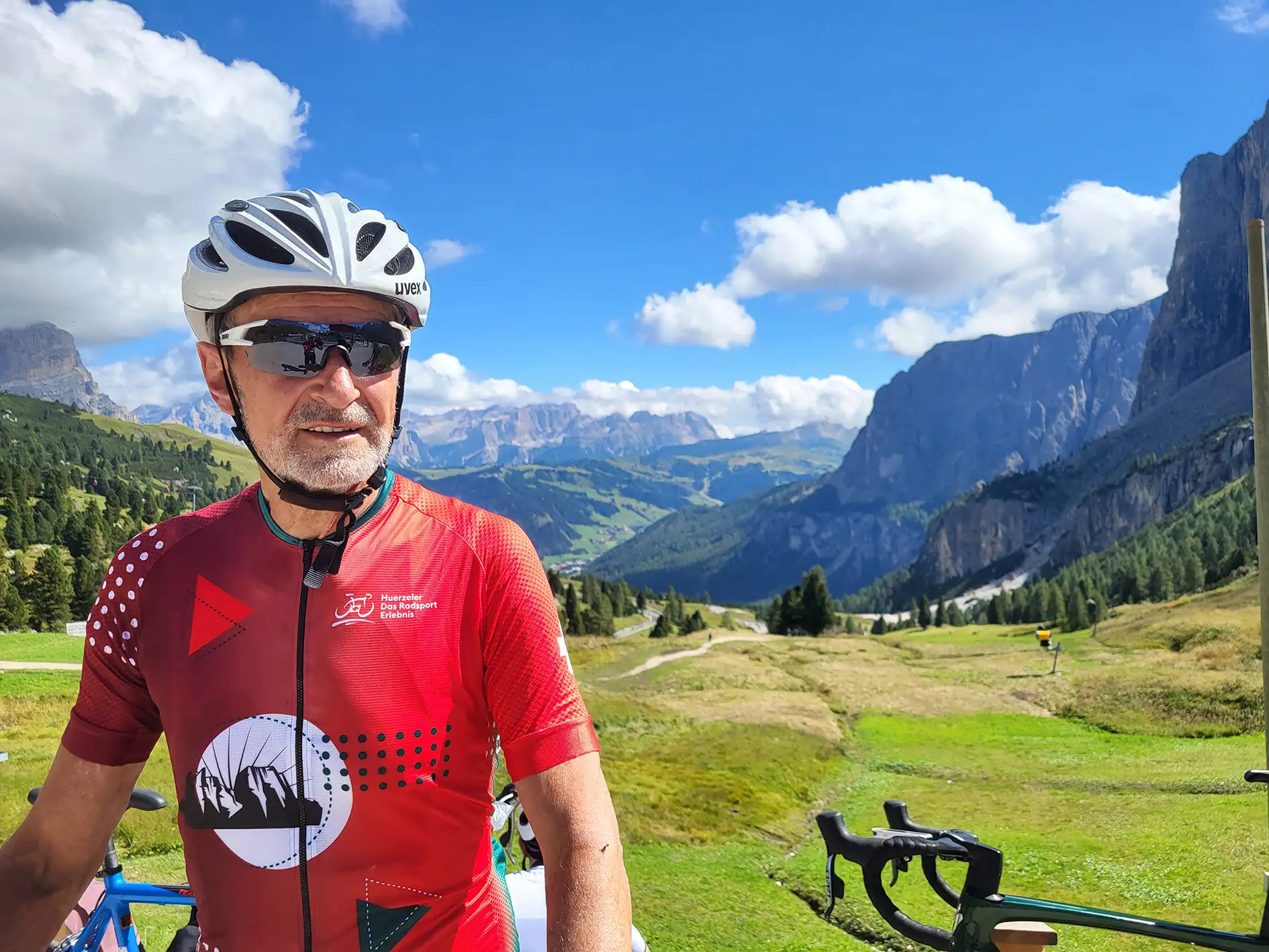 Herbert Lauble, Geschäftsleiter bei CasaVitale, an einem sonnigen Tag, mit seinem Fahrrad auf Radtour in den Alpen vor einer herrlich malerischen Berglandschaft.